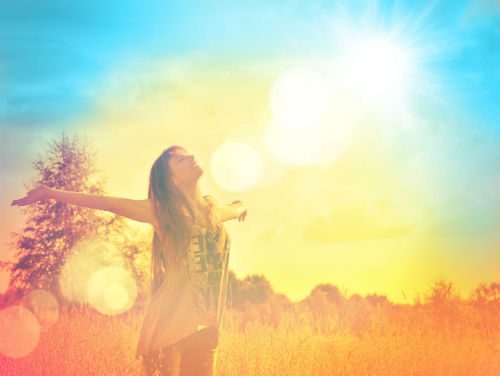 A woman standing in the grass with her arms outstretched.