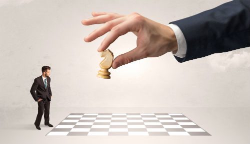 A hand holding a chess piece over the chessboard.